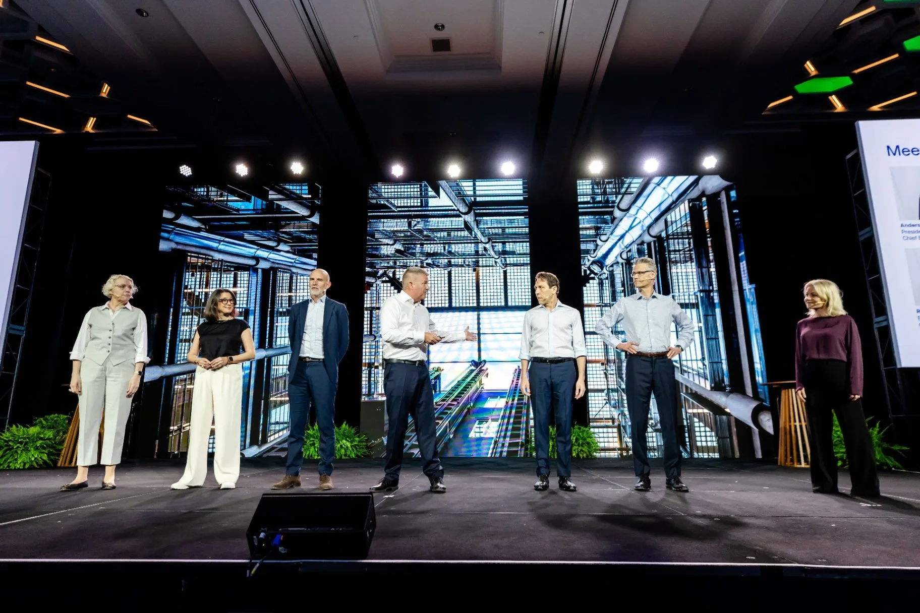 Panel of presenters standing together on a conference stage